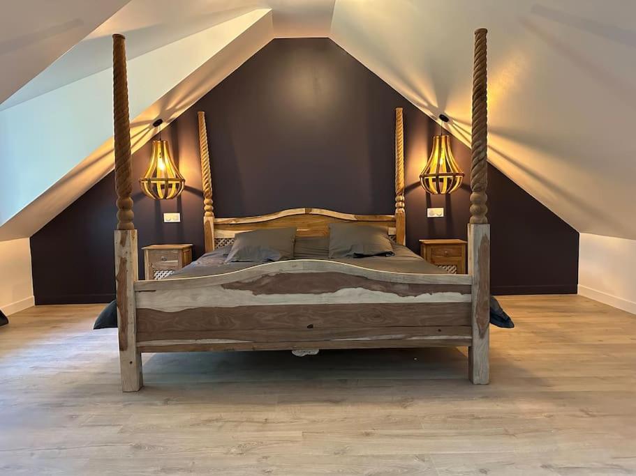 - une chambre mansardée avec un grand lit en bois dans l'établissement Love room l escapade, à Guitrancourt