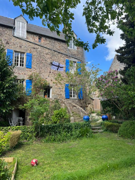 un vieux bâtiment en briques avec des fenêtres bleues et une cour dans l'établissement Maison de famille proche St Malo, à Châteauneuf-dʼIlle-et-Vilaine