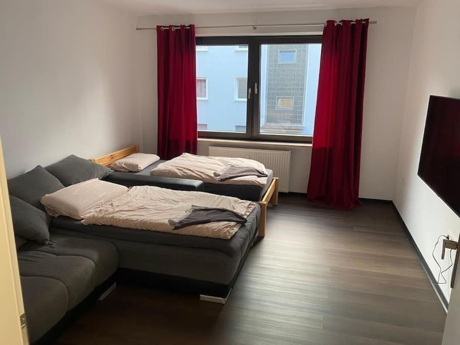 two beds in a room with a couch and a window at 1 Zimmer Ferienwohnung in Essen in Essen