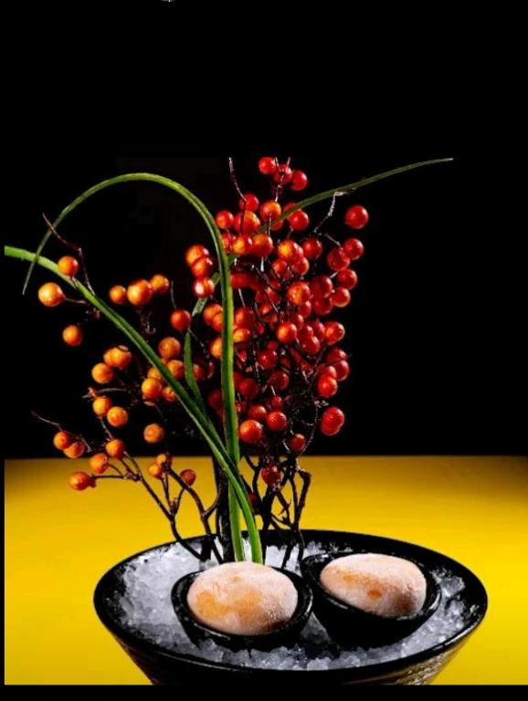 a black vase with a bunch of berries in it at AG Hotel in Abu Dhabi