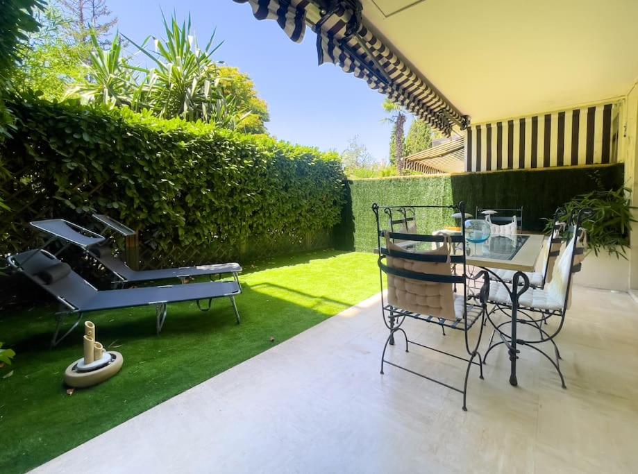 un patio avec une table et des chaises dans une cour dans l'établissement Rénové, grande terrasse, piscine, au calme absolu, à Cannes