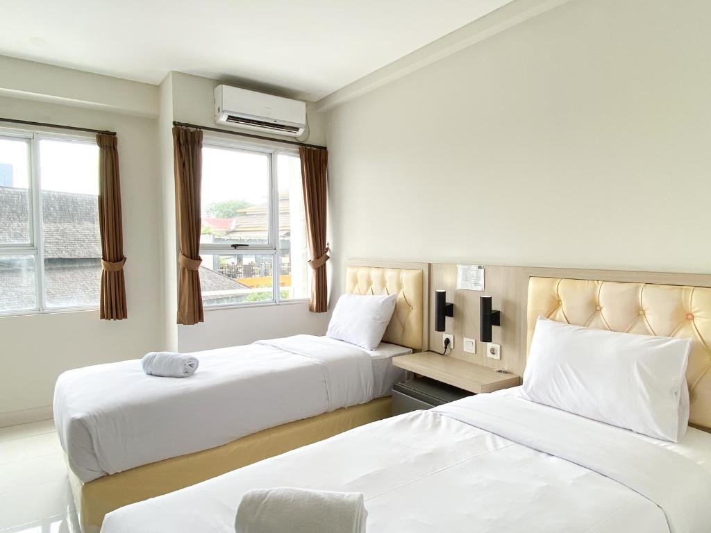 a hotel room with two beds and two windows at Good Choice and Comfy Studio (No Kitchen) at Elvis Tower Apartment By Travelio in Cikarang