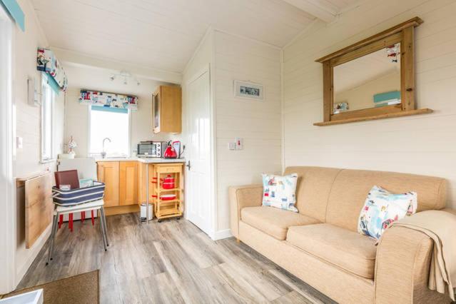 a living room with a couch and a kitchen at Seal Cabin in Strangford