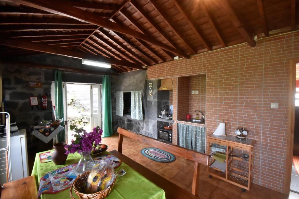 a living room with a table and a brick wall at Adega do Gato in Calhau