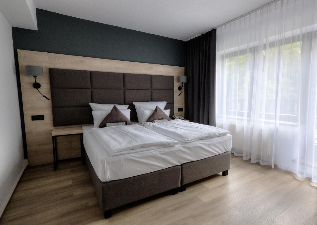 a bedroom with a large bed and a large window at Waldhotel Wandlitz in Wandlitz