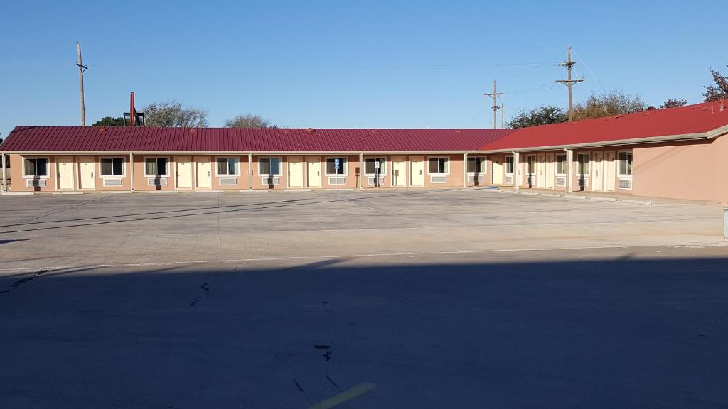 un edificio con techo rojo y aparcamiento en Denver City Motel en Denver City