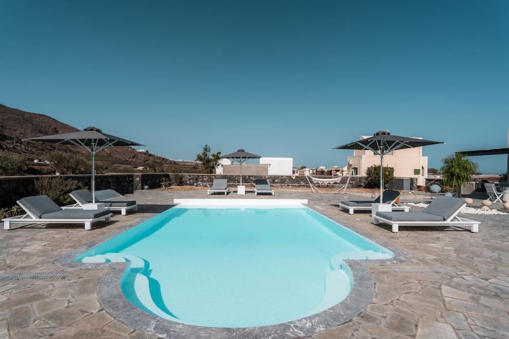 a large swimming pool with chairs and umbrellas at Mythique Pool Residence in Foinikiá