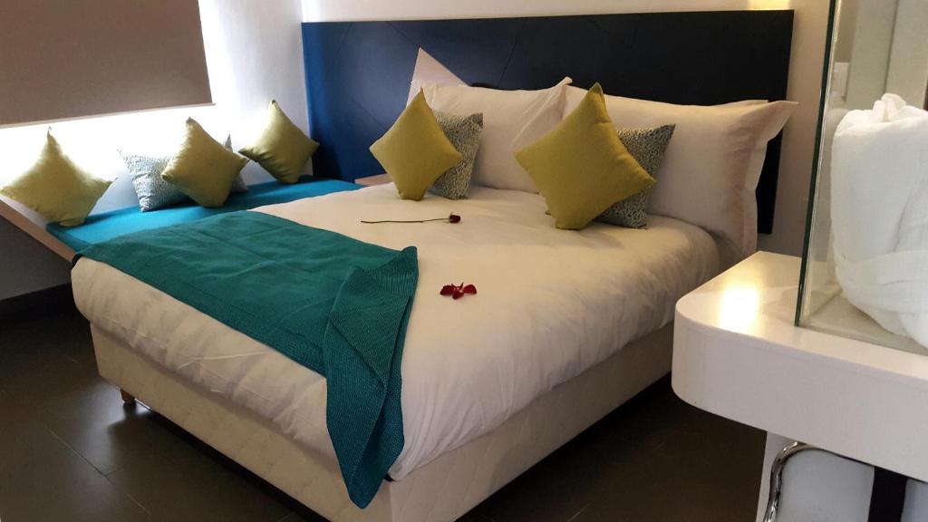 a bedroom with a bed with a green blanket on it at Relax Hôtel Oujda in Oujda