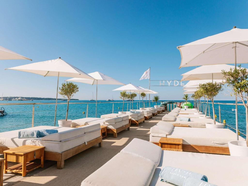 a row of white lounge chairs and umbrellas on the water at Mondrian Cannes in Cannes