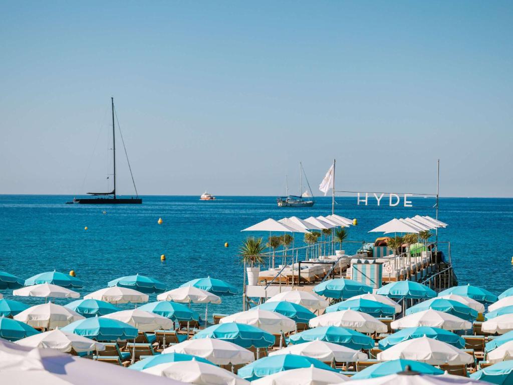 a bunch of blue and white umbrellas on a beach at Mondrian Cannes in Cannes