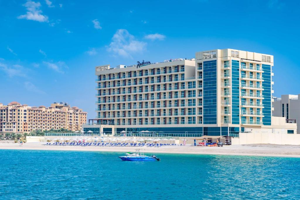 um barco na água em frente a um grande edifício em Radisson Resort Ras Al Khaimah Marjan Island em Ras al-Khaimah