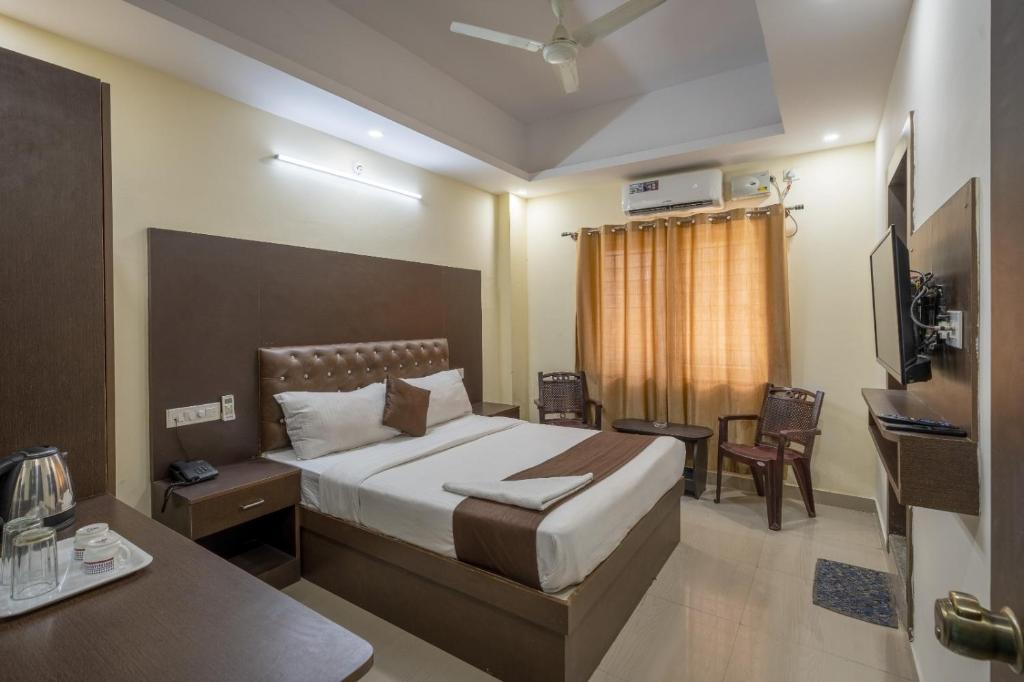 Dormitorio con cama, escritorio y TV en PPH Living Royal GS Comforts, en Bangalore