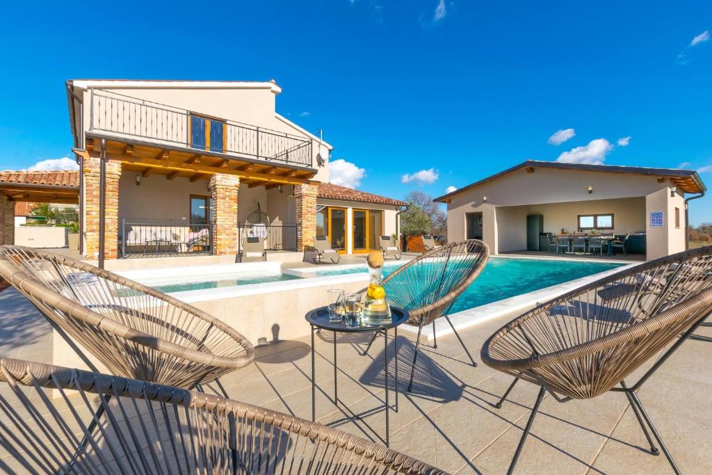 patio z 2 krzesłami i stołem przy basenie w obiekcie Relaxing pool villa Mattuzzi in Loborika w mieście Loborika