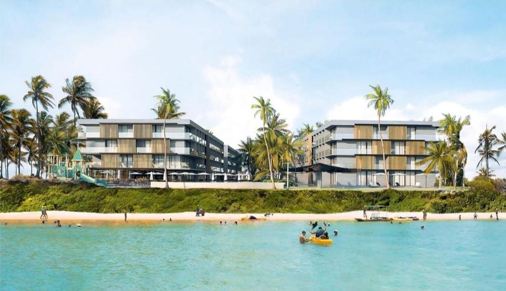 a group of hotels on a beach with a boat in the water at Paraíso Porto Alto in Porto De Galinhas