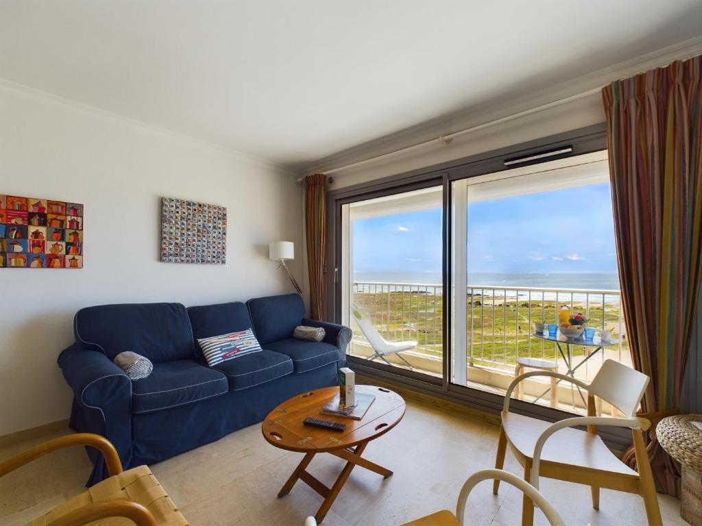 un salon avec un canapé bleu et une grande fenêtre dans l'établissement Escapade en duo - Vue et emplacement privilegiés, à Les Sables-dʼOlonne