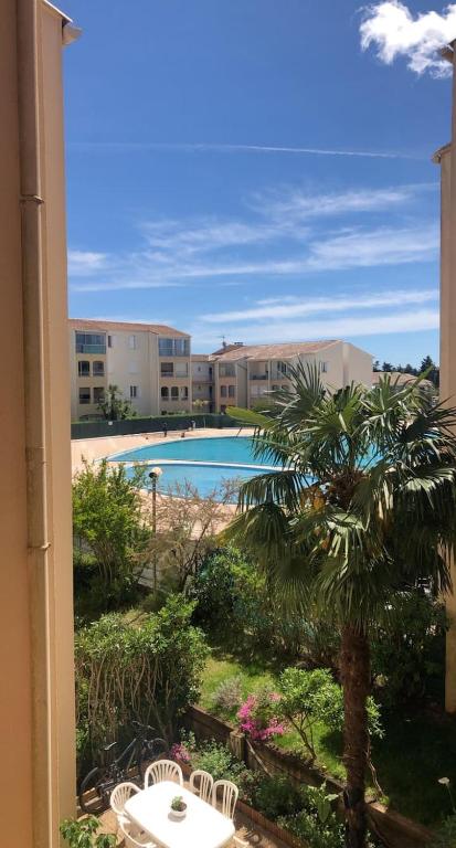 - une vue sur la piscine et un palmier dans l'établissement Un cocon aux marquises - Joli T2 Dégagée Sud- ouest Piscine Tennis, à Fréjus