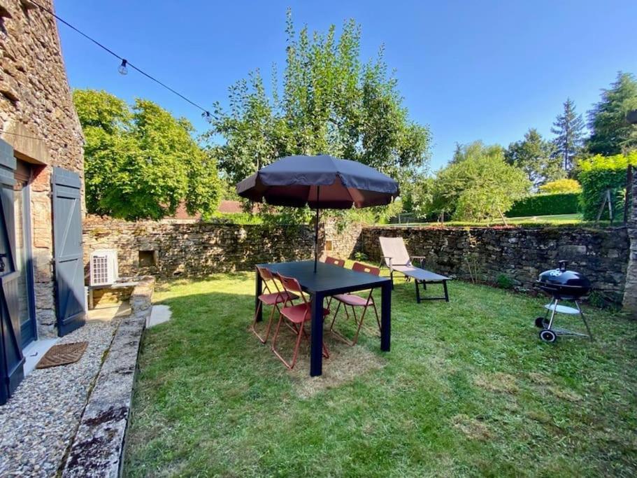 a table with an umbrella and chairs in a yard at Maisonnette avec jardin in Chamilly