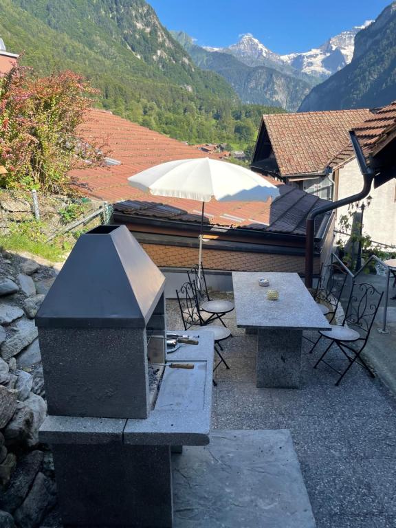 a patio with a table and an umbrella and chairs at Vintage Apartment By Apartments Capricorn in Gsteigwiler