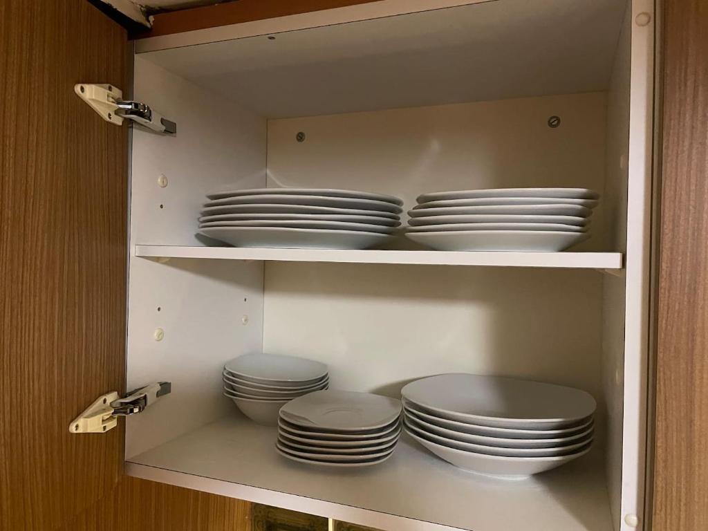 a cabinet filled with white plates and bowls at Vintage Apartment By Apartments Capricorn in Gsteigwiler