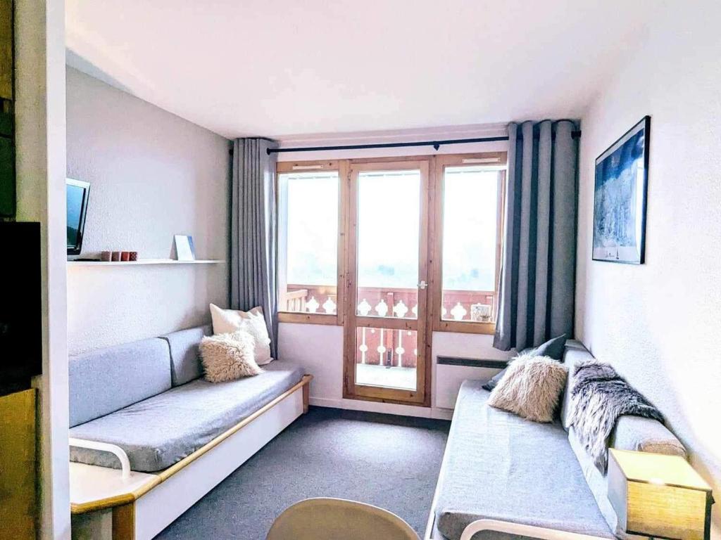 un salon avec un canapé et une fenêtre dans l'établissement Appartement rénové au pied des pistes avec balcon et casier à skis - FR-1-181-2064, à La Plagne Tarentaise