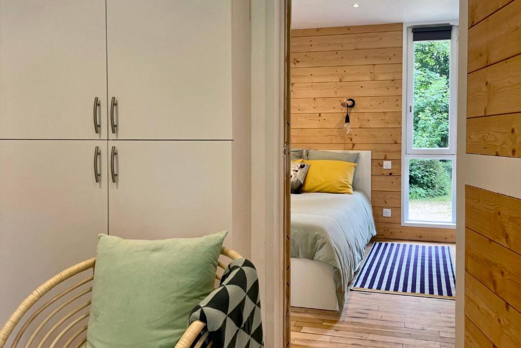 ein Schlafzimmer mit einem Bett, einem Fenster und einem Stuhl in der Unterkunft Le Bungalow in Bonningues-lès-Calais