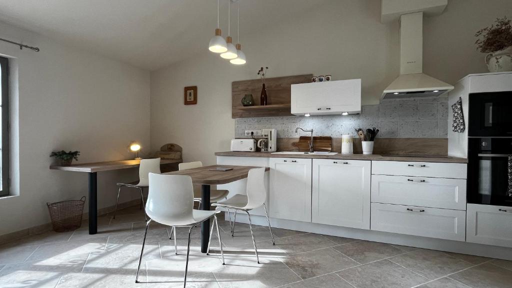 une cuisine avec des armoires blanches et une table et des chaises dans l'établissement Un Cottage au pied du Ventoux, à Bédoin
