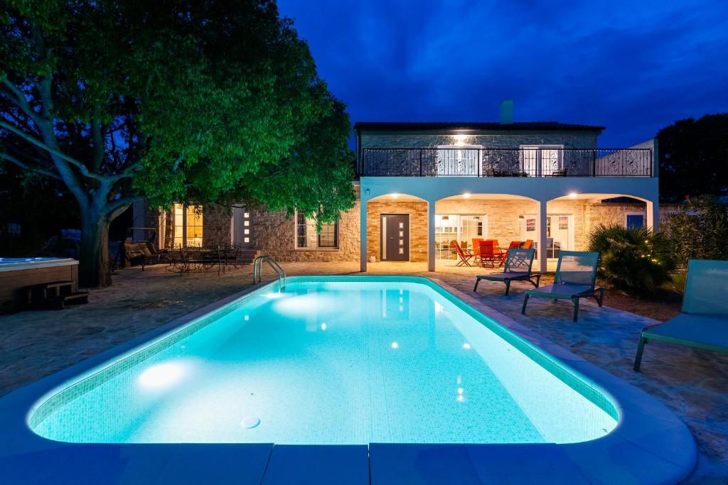 una piscina frente a una casa por la noche en Villa Agape - heated pool, en Raštević