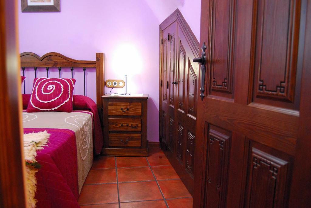 a bedroom with a bed and a dresser next to a door at Casa El Rincón del Ángel in Bubión