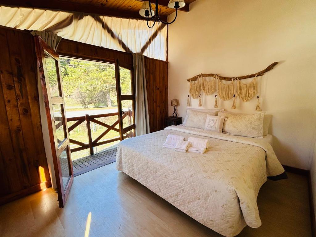 a bedroom with a large bed and a large window at Cabañas Quijote in Lago Puelo