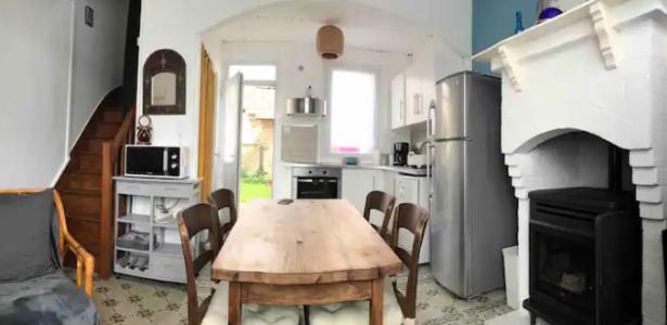 une cuisine avec une table en bois et une cuisine avec une cheminée dans l'établissement Maison de vacances bord de mer à Lion sur Mer, à Lion-sur-Mer