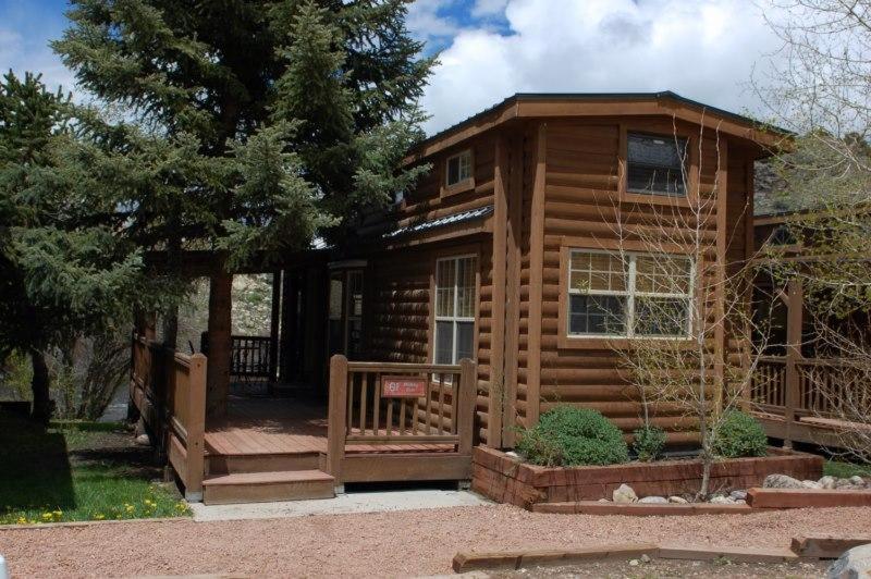 a log cabin with a porch and a fence at Cabin 61 in Almont