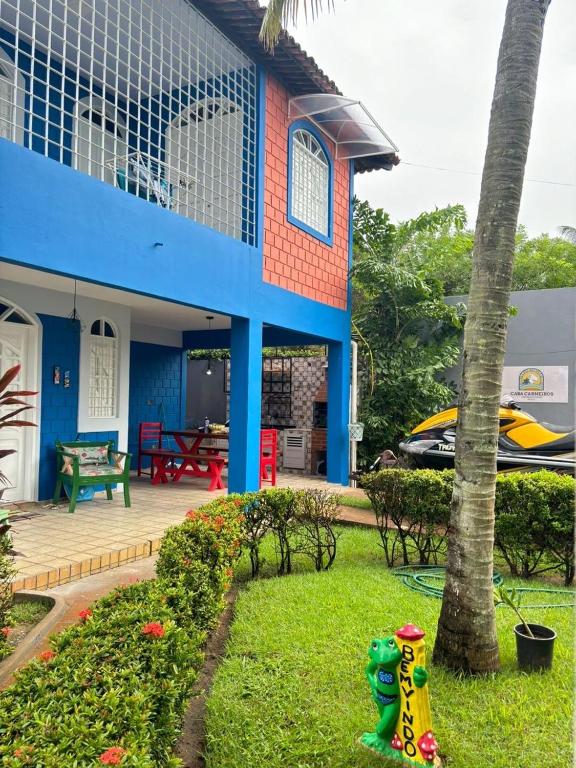 ein blau-rotes Haus mit einem Garten davor in der Unterkunft Carneiros House in Praia dos Carneiros