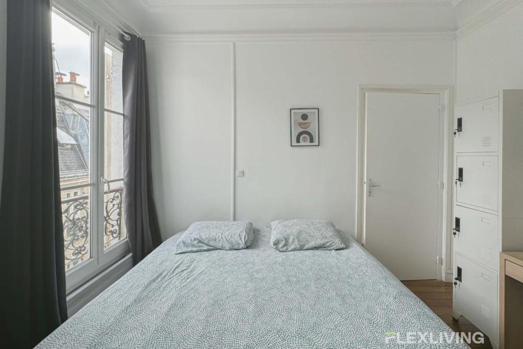 une chambre avec un lit et une grande fenêtre dans l'établissement Flexliving - room - Lemoine, à Paris