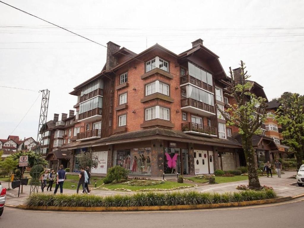 a large brick building with people walking in front of it at Apartamento a 300m da Rua Coberta de Gramado in Gramado