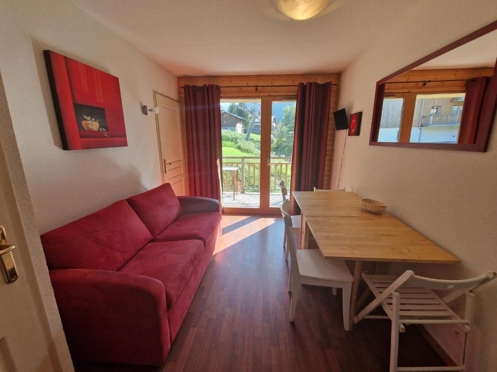 un salon avec un canapé rouge et une table en bois dans l'établissement Appart 2 pièces, 4 pers, proche télécabine et commerces, balcon au sud, casier à skis - FR-1-265-206, à Valfréjus