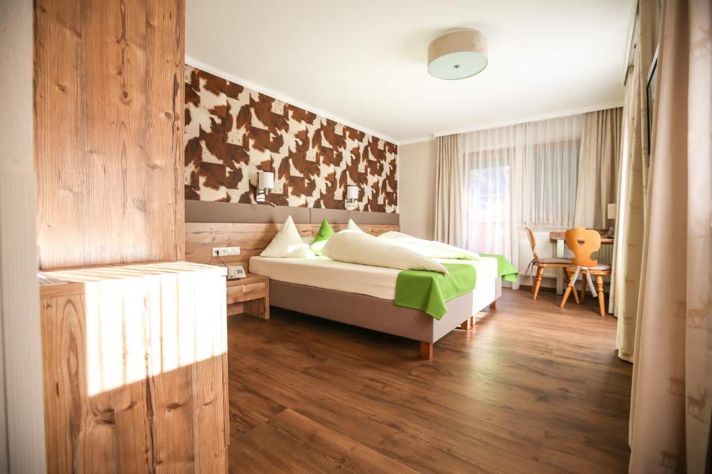 a bedroom with a bed and a table and a chair at Hotel Landhaus Carla in Mayrhofen