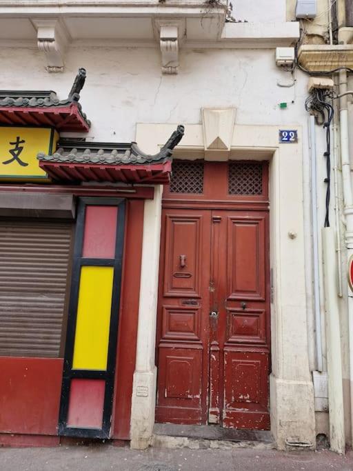 une porte rouge d'un bâtiment avec un panneau sur celui-ci dans l'établissement Le Lotus - appartement, à Béziers