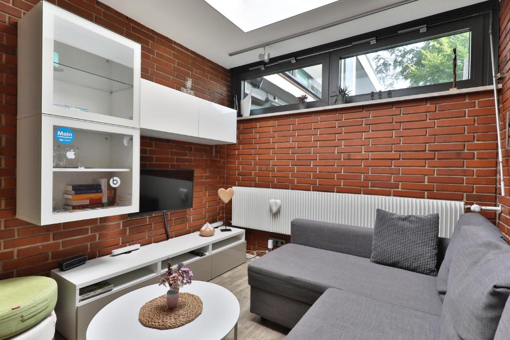 a living room with a couch and a brick wall at Ferienwohnung nahe A8 Augsburg München Ulm - Stillblick in Gersthofen