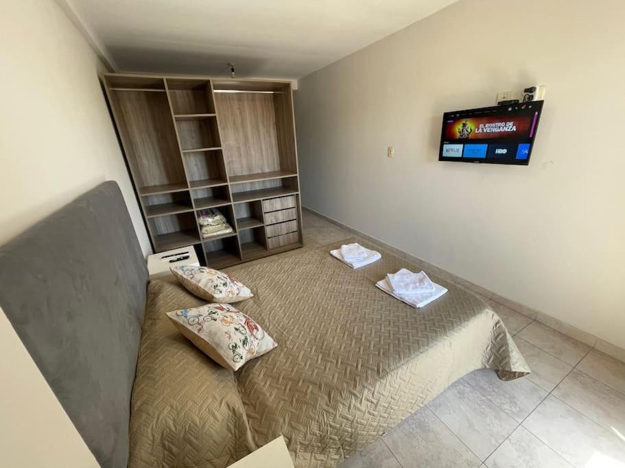 ein Schlafzimmer mit einem Bett und einem Fernseher an der Wand in der Unterkunft Dpto en av mate de luna, en el medio de la ciudad in Villa Luján