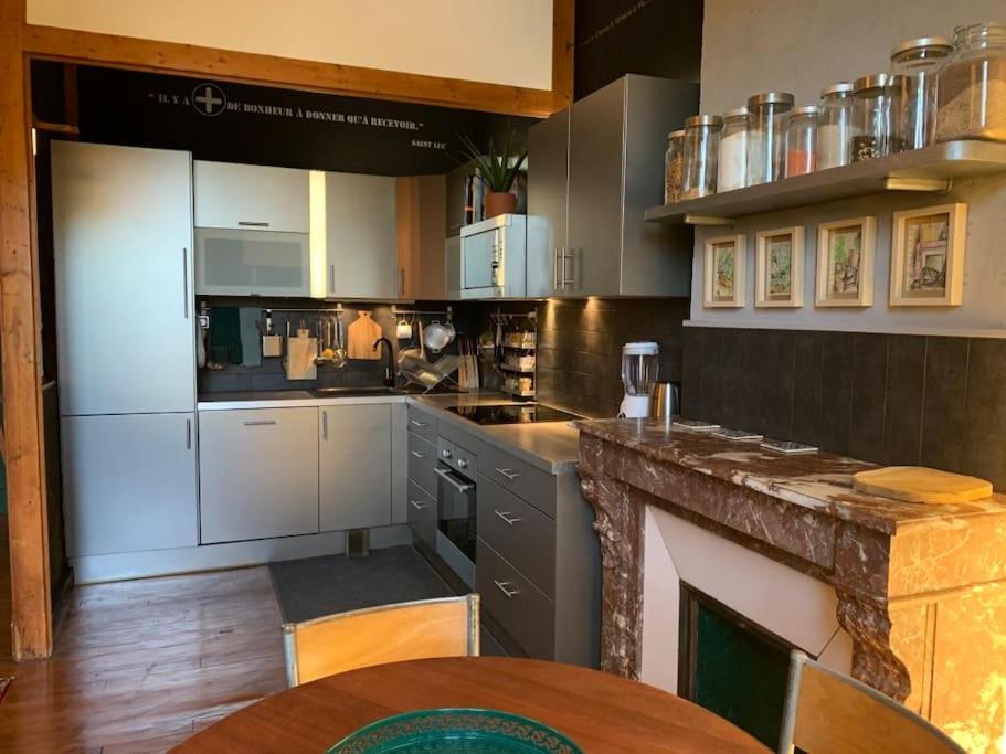 une cuisine avec des armoires blanches et une table à l'intérieur dans l'établissement Cosy appart, à Saint Etienne