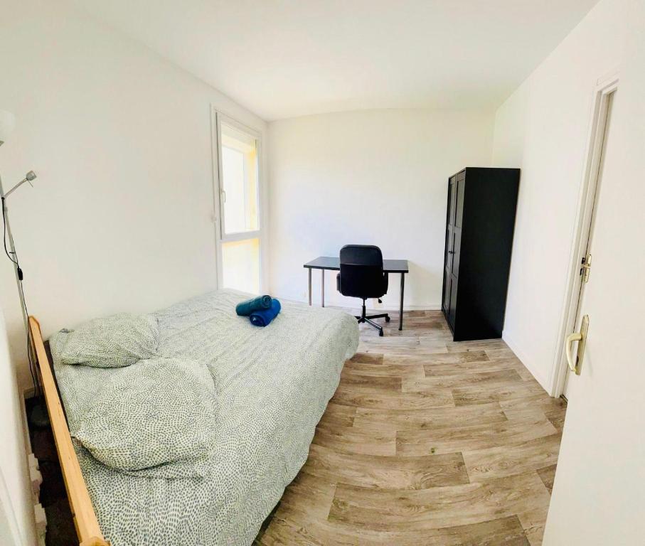 une chambre avec un lit et un bureau avec une chaise dans l'établissement Bel appartement tout confort, à Saint-Quentin