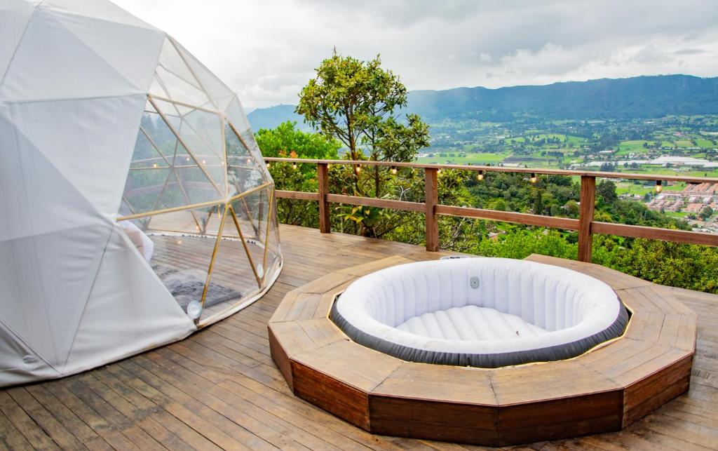 una cupola di vetro situata sopra un ponte di legno di Glamping Yáku a Tenjo