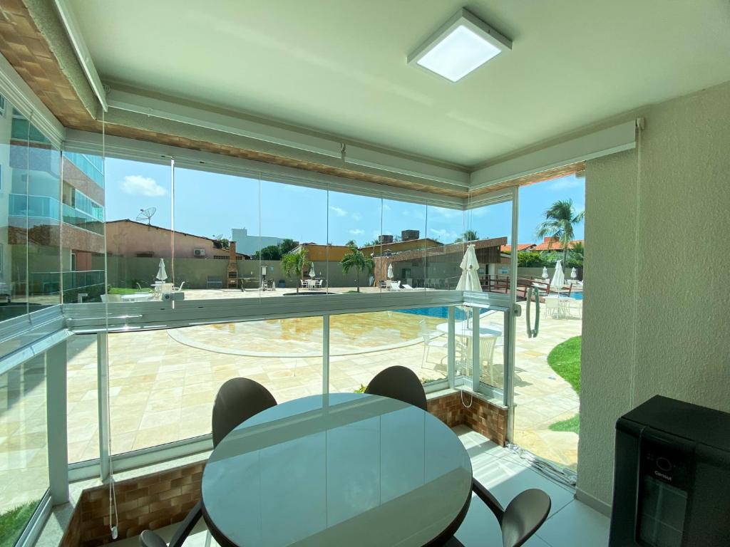 ein Glasraum mit Tisch und Stühlen und einem großen Fenster in der Unterkunft Porto Cayman Residence - Melhor trecho da Praia de Tamandaré in Tamandaré
