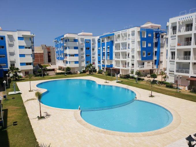a large swimming pool in front of some apartment buildings at Belle Appartement & Résidence Avec Piscine& A 10min de la plage- Martil-Tétouan in Martil