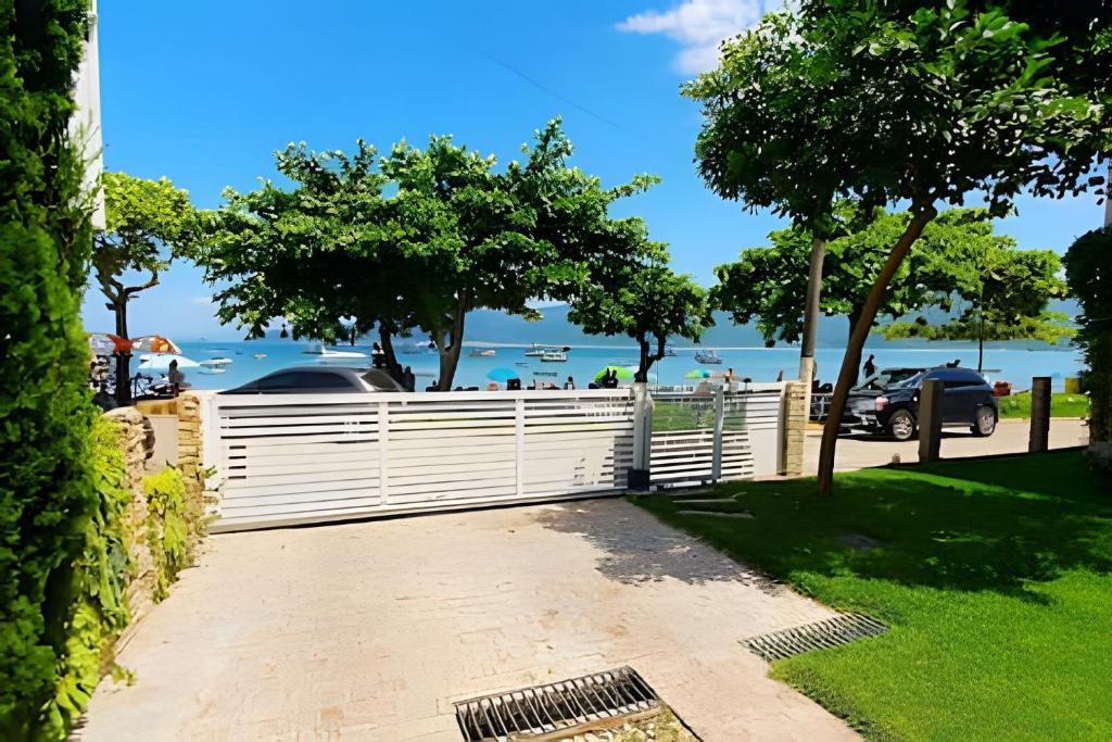 a white fence with a view of the water at Aconchego à Beira-Mar em Gov Celso Ramos/SC in Armação