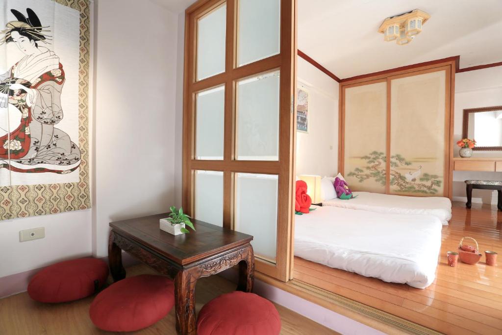 a room with a bed and a table and a mirror at Flower Bird House B&B in Jiaoxi