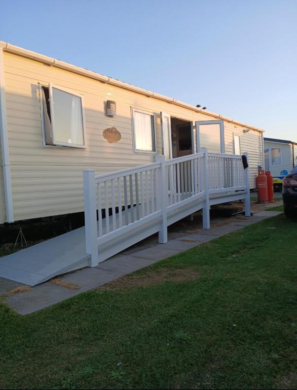 a mobile home with a porch and a white railing at Accessible and dog friendly caravan in Ingoldmells