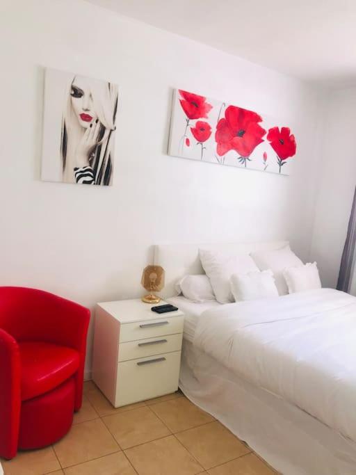 une chambre avec un lit et une chaise rouge dans l'établissement logement tout proche de la plage, à Cannes