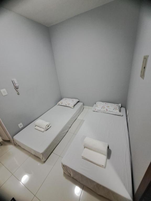 Dos camas en una habitación con paredes blancas. en Estúdio 116 - Asa Sul, en Brasilia