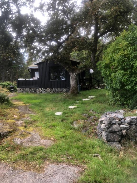 a house with a tree and a stone wall at Ikigaiisättra 44 in Åkersberga